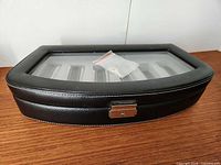 Closed black leather watch case showing glass lid and six interior slots