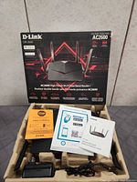 Front of box and contents showing router, antennas, adapter, manuals