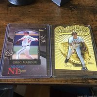 Both Greg Maddux cards in sleeves side by side