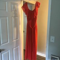 Front view of full-length red dress with ruffle neckline and waist tie