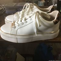 Left and right sides of the Aldo white platform sneakers showing profile, platform sole, gold trim, tortoiseshell heel detail