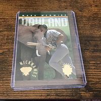 Front of card in plastic holder showing Mark McGwire batting, elephant background