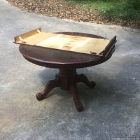 Round oak pedestal table with leaf underside displayed on top