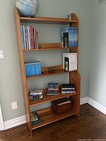 Front view of tall solid wood bookshelf with books and globe on top