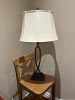 Full view of one lamp on chair showing base, stem, shade