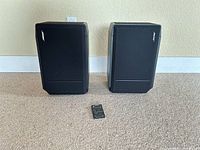 Front view of both Bose speakers with remote in foreground