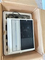 Projector in foam insert inside box, power cord visible