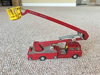 Left side profile showing red fire engine, extended ladder arm, yellow bucket