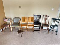 Front view of all seven chairs and footstool aligned against wall