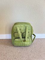 Front view showing green quilted nylon carry-on with exterior pockets and straps