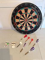 Front view of dartboard with darts, flights, sharpener and holder laid out