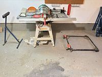 Table saw on stand, roller support, mobile dolly and accessories on tabletop
