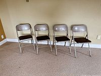 Front view of four beige metal Samsonite folding chairs with brown laminate seats