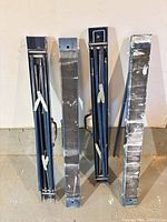 Four collapsed blue metal sawhorses standing upright