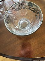 Top view of clear etched glass bowl showing silver rim and floral vine decoration