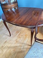 Full view of table showing oval shape, mahogany finish, cabriole legs, center seam