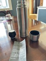 Thermos with stopper, cup lid and paper insert shown