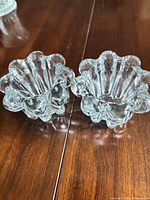 Pair of clear pressed glass votive holders showing side profile and ruffled edges