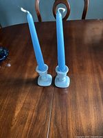 Pair of light blue ceramic candlestick holders with blue tapers on wooden table