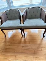 Front view of both armchairs showing upholstery, cane sides, carved legs