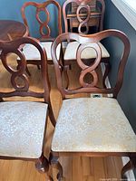Four cherry finish dining chairs with cream floral damask seats