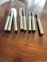 Set of four stainless spreader knives and four appetizer forks on table