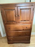 Front view of solid pine dresser showing cabinet doors, three drawers, wooden knobs, natural finish