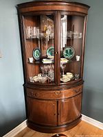 Full view of corner curio cabinet showing glass display section and lower storage