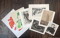 Group shot of eight assorted unframed prints laid out on floor