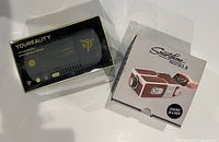 Sealed iJoy Youreality VR headset box next to boxed Smartphone Projector 2.0