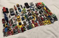 Wide overhead view of entire mixed toy vehicle collection spread on white background