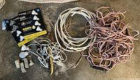 Overview of all items laid out on floor: boxed LED bulbs, loose bulb, adapters, tangled white cords, pink cord bundle, white NM cable coil