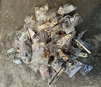 Large pile of individually bagged gold and silver tone metal purse hardware on floor