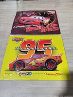 Both metal signs laid flat showing full graphics and plastic wrap.