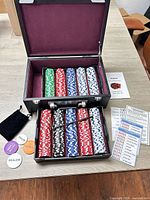 Open case showing two tiers of racked multicolor poker chips, accessories and interior lining