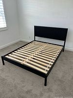 Full view of assembled queen bed frame showing headboard, frame, and slats