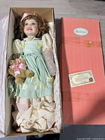 Doll in open box with lid and certificate visible