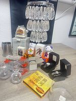 Group view of entire lot including chandelier, crystal bottles, pewter flagon, wax warmer box, ornament, bears, watches, CD set and trading card packs