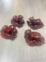 Four cinnabar baby figurines grouped on floor