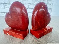 Front view of both red alabaster heart bookends on bases