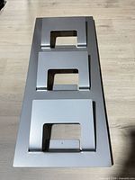 Front view of entire silver three-slot wall magazine rack
