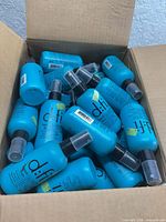 Open box showing numerous identical blue D:fi spray bottles