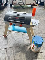 Front view of wooden play grill and bucket of blocks