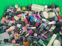Top view of green bin showing large assortment of nail polish bottles, Coach lotion and skin cream jar
