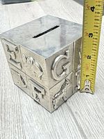 Cube coin bank showing measurement of side ~3 inches