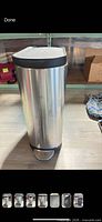 Front view of stainless steel trash can with foot pedal and black lid