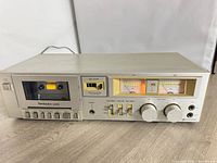 Front view of Technics M205 cassette deck showing cassette well, VU meters, controls and overall chassis