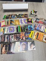 Overview of hundreds of assorted trading cards spread on table with white card storage box