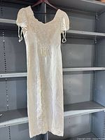 Full front view of ivory satin wedding dress hanging, showing length and sleeve style