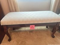 Full front view of wood bench showing upholstered seat